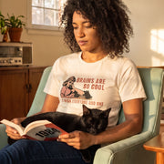 Brains Are So Cool retro-inspired graphic tee on woman reading book with black cat asleep on her lap — Galactic Ink Club
