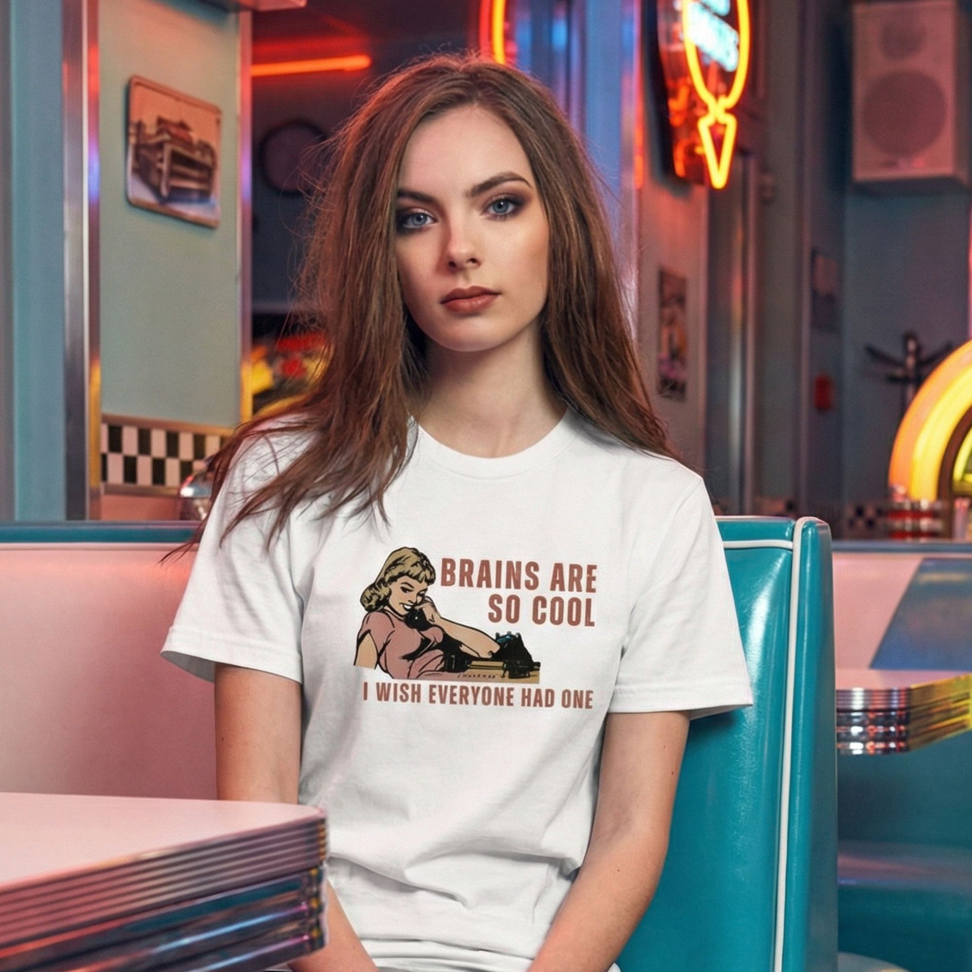 Brains Are So Cool retro-inspired graphic tee on woman sitting in retro diner with neon signage — Galactic Ink Club
