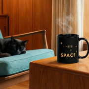 Deep Space retro graphic mug on mid-century modern side table with sleeping black cat and teal chair — Galactic Ink Club