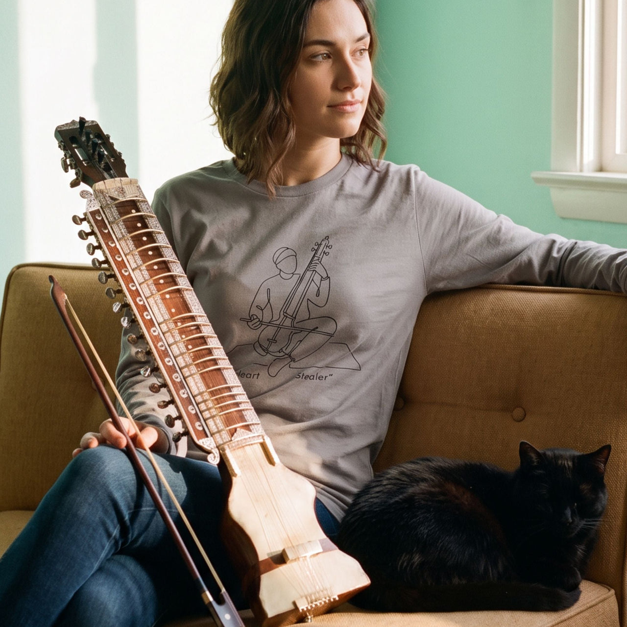 Mid-century Dilruba retro-inspired graphic long sleeve shirt on woman sitting on couch holding Dilruba instrument with black cat beside her — Galactic Ink Club
