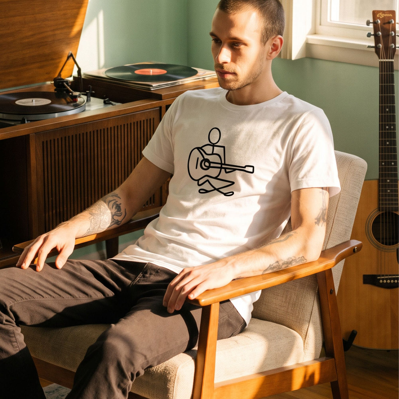 Guitar Player Retro-Inspired Graphic Tee on man sitting near acoustic guitar and record player — Galactic Ink Club
