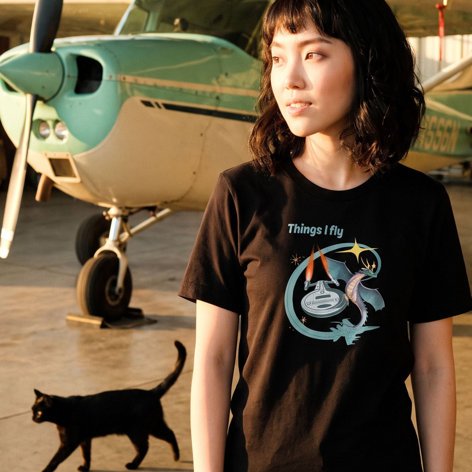Things I Fly retro-inspired graphic tee on woman in a hangar with black cat — Galactic Ink Club
