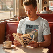 Wake Up! retro-inspired graphic tee worn by man reading Paper Bullets in retro diner booth with steaming coffee — Galactic Ink Club